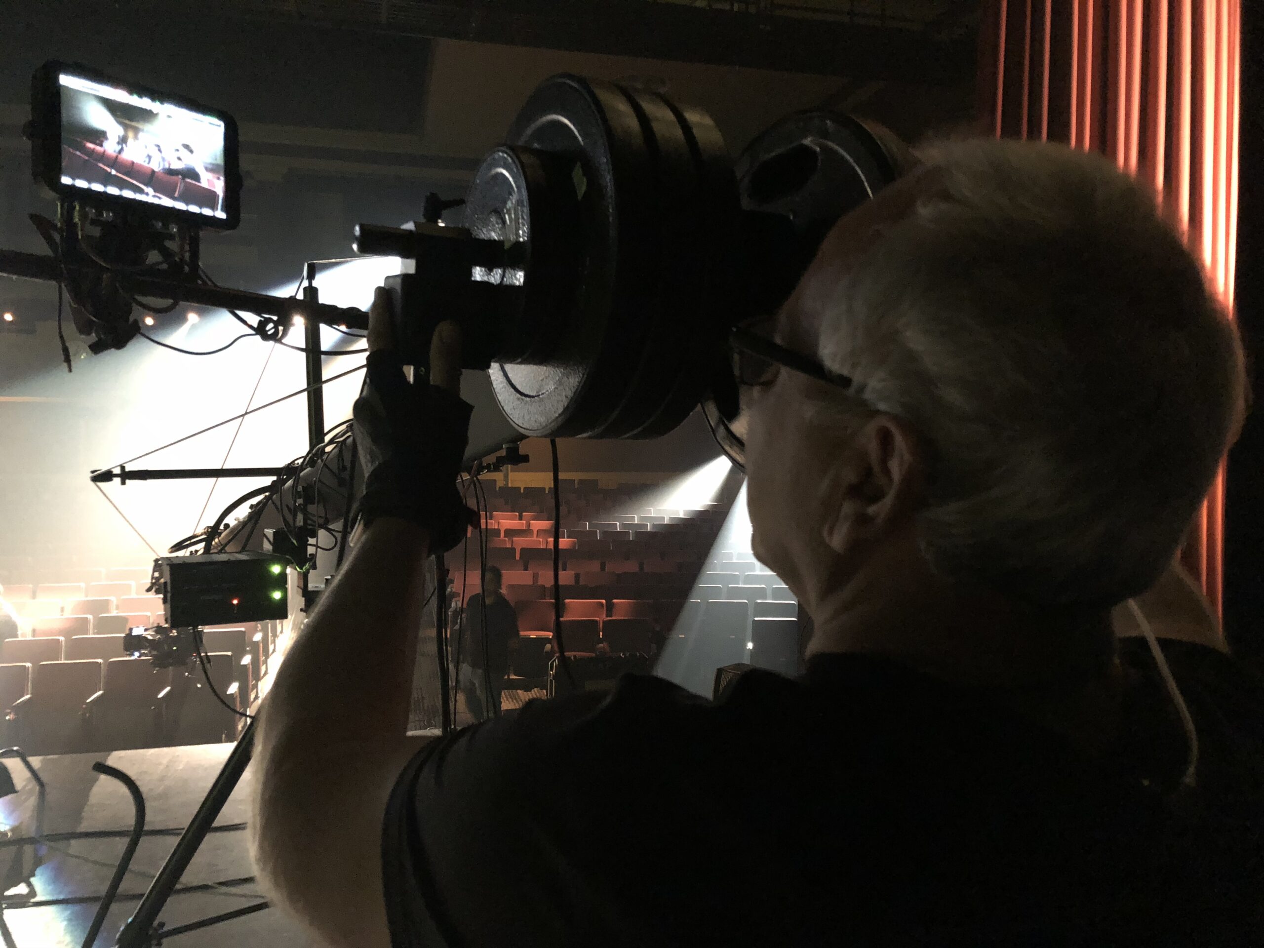 Cameraman behind the camera on a stage facing out into the audience