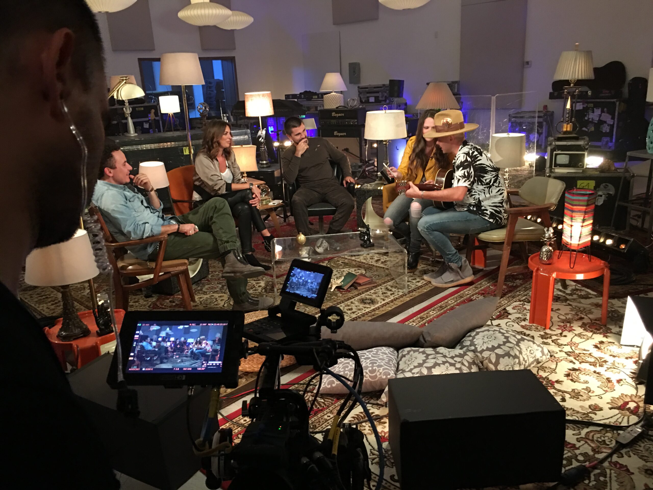 Juanes Music Studio live show with Juanes and guest – Pilot, with DP Angel Barroeta, showing ceiling lights, floor lamps and table lamps. In the forground you can see the camera with the camera operator.